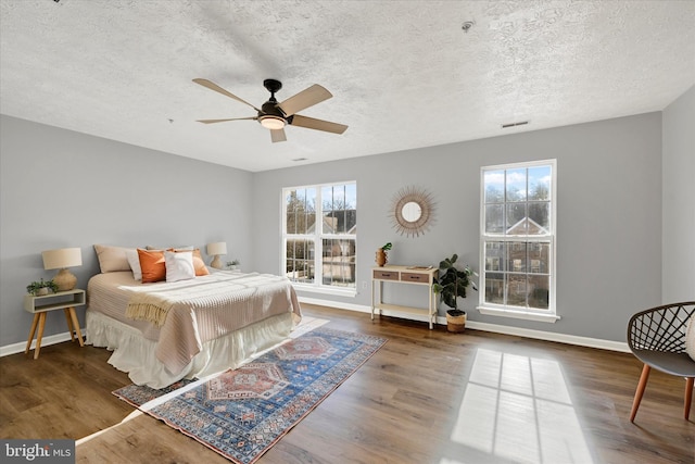 bedroom featuring a textured ceiling, ceiling fan, and dark wood-type flooring