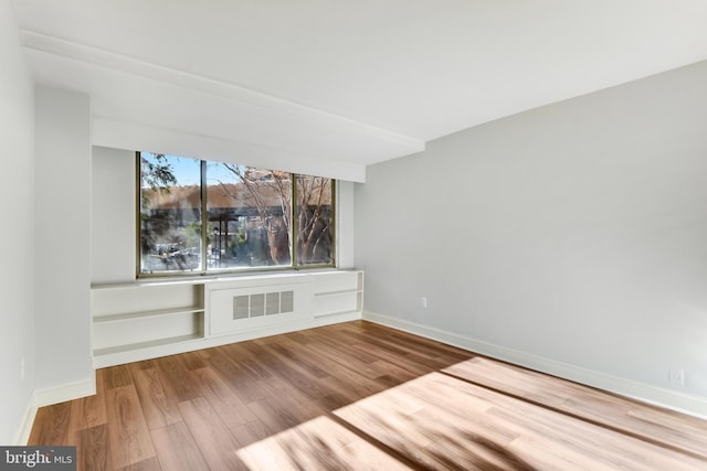 unfurnished living room featuring hardwood / wood-style flooring and radiator