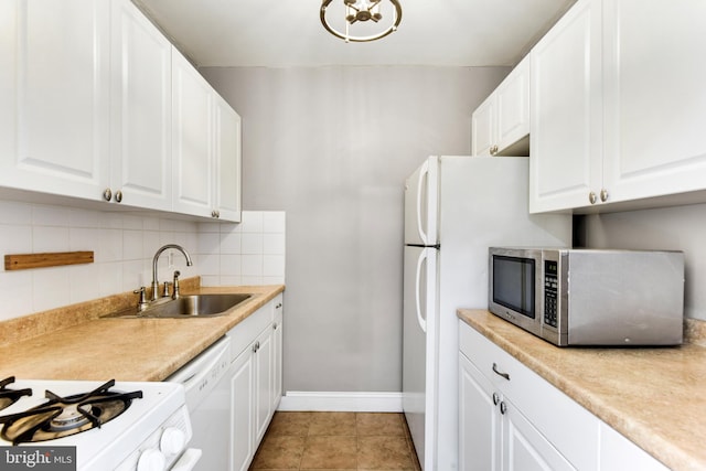 kitchen with tasteful backsplash, white dishwasher, sink, light tile patterned floors, and white cabinets