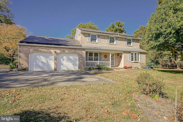 view of front of property with a front yard, a garage, a porch, and solar panels