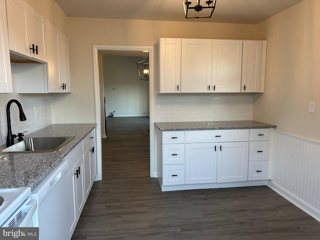 kitchen with white cabinets, dishwasher, light stone counters, and sink