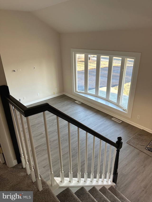 stairs with wood-type flooring and vaulted ceiling