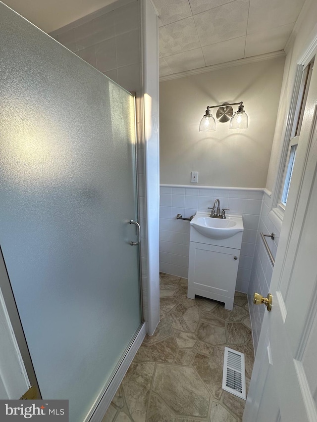 bathroom with vanity, tile walls, and walk in shower