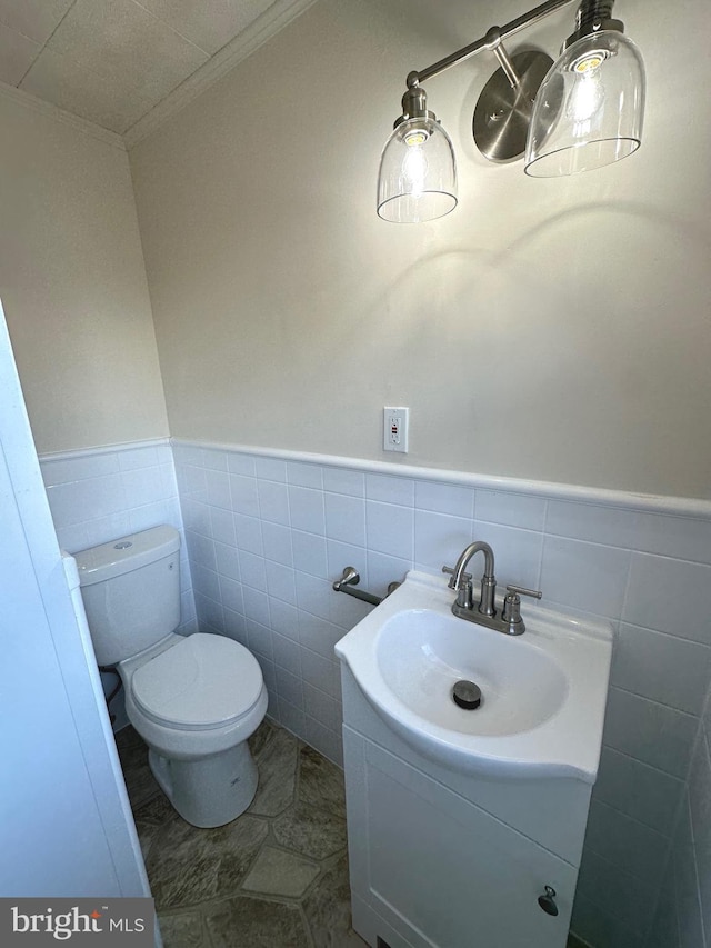 bathroom featuring vanity, ornamental molding, tile walls, and toilet