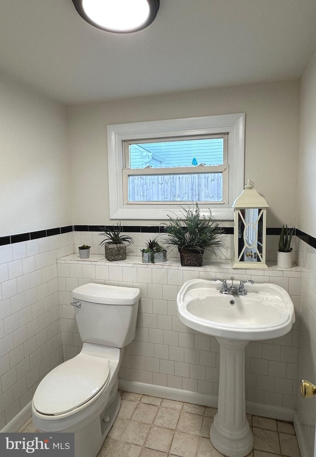 bathroom featuring tile patterned flooring, tile walls, and toilet