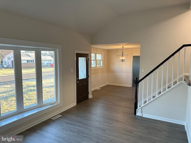 entryway featuring dark hardwood / wood-style flooring, lofted ceiling, and an inviting chandelier