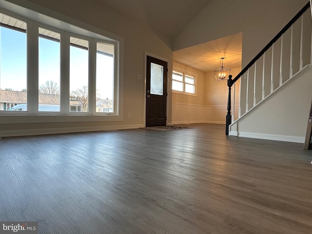 entrance foyer featuring vaulted ceiling, dark hardwood / wood-style flooring, and an inviting chandelier