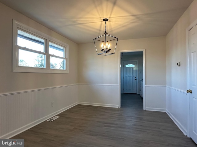 unfurnished dining area featuring dark hardwood / wood-style floors and an inviting chandelier