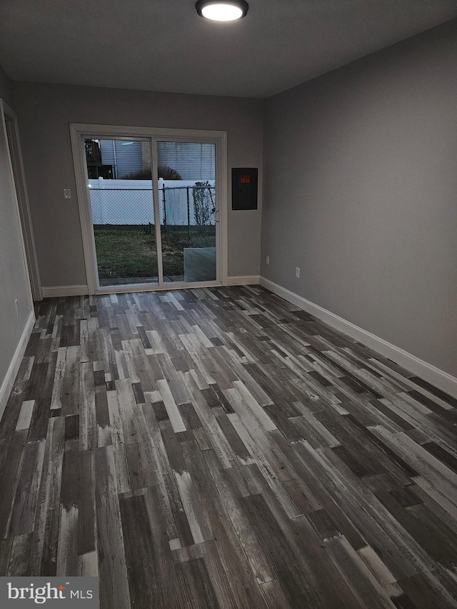 spare room featuring electric panel and dark hardwood / wood-style floors