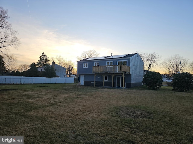 back house at dusk with a yard and a deck