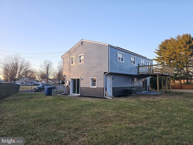 back of property featuring a lawn, cooling unit, and a deck