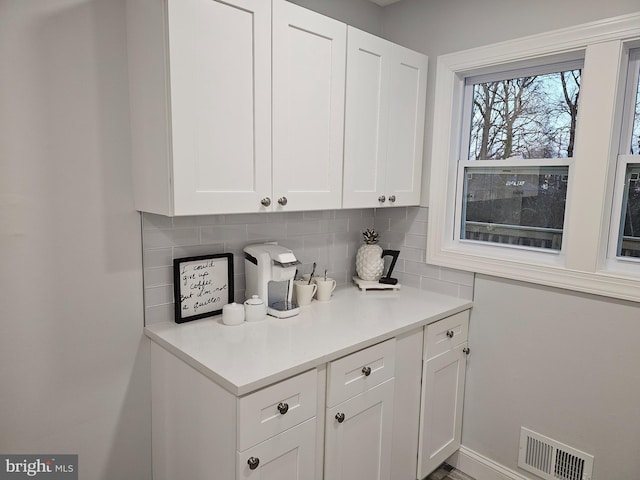 bar featuring tasteful backsplash and white cabinetry