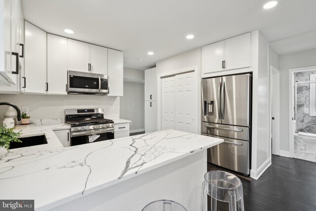 kitchen with appliances with stainless steel finishes, sink, white cabinets, and light stone counters