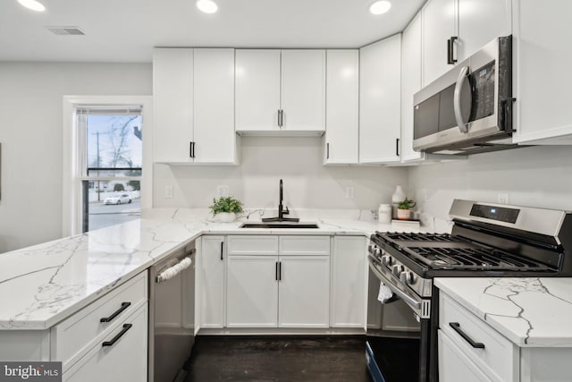 kitchen featuring stainless steel appliances, white cabinetry, sink, and light stone counters