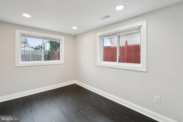 spare room featuring a wealth of natural light and dark hardwood / wood-style flooring