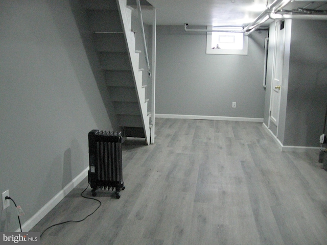 basement featuring light wood-type flooring and radiator