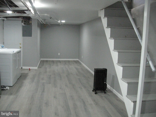 basement featuring electric panel, light hardwood / wood-style floors, and washing machine and clothes dryer