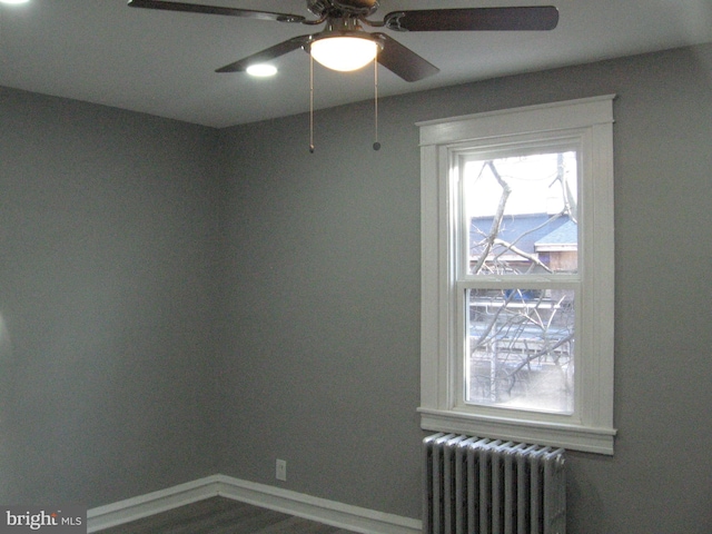 empty room with hardwood / wood-style floors, radiator, and ceiling fan