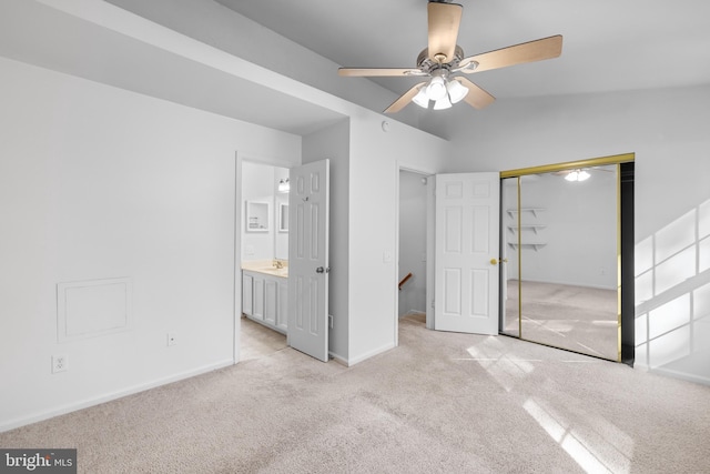 unfurnished bedroom with ceiling fan, connected bathroom, light carpet, vaulted ceiling, and a closet