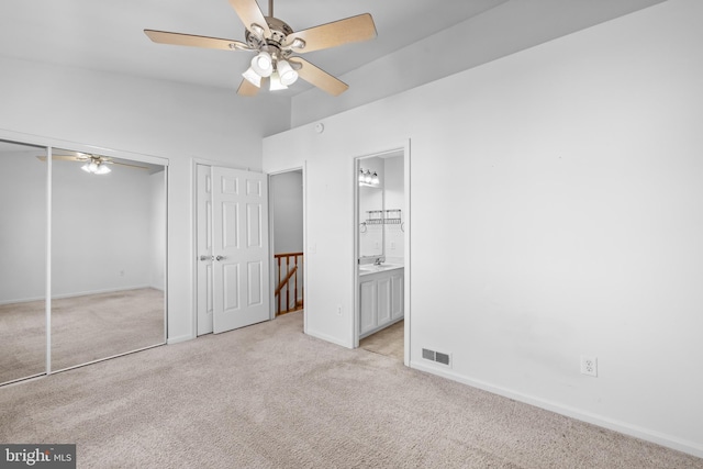 unfurnished bedroom with ensuite bathroom, sink, light colored carpet, a closet, and ceiling fan