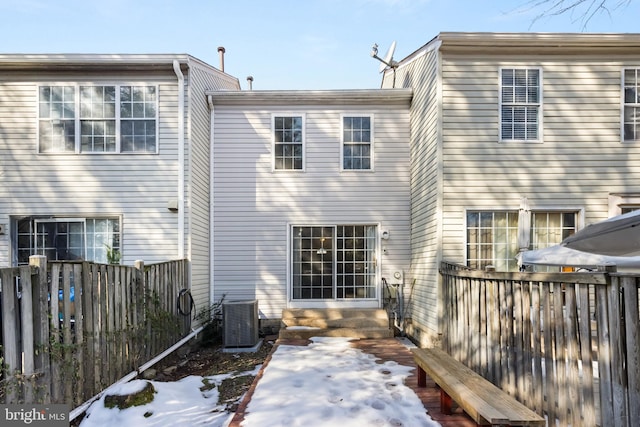 snow covered rear of property featuring cooling unit