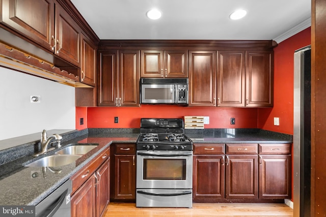 kitchen featuring sink, crown molding, light hardwood / wood-style flooring, appliances with stainless steel finishes, and dark stone counters