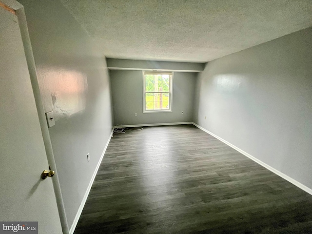 empty room with dark hardwood / wood-style flooring and a textured ceiling