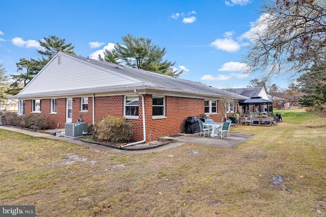 rear view of house featuring a gazebo, central AC unit, a patio area, and a lawn