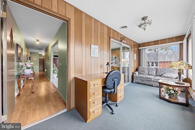 office space featuring light carpet and wooden walls