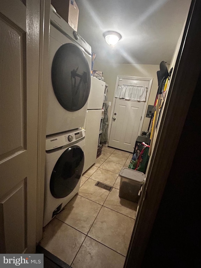 laundry room featuring stacked washing maching and dryer and light tile patterned flooring