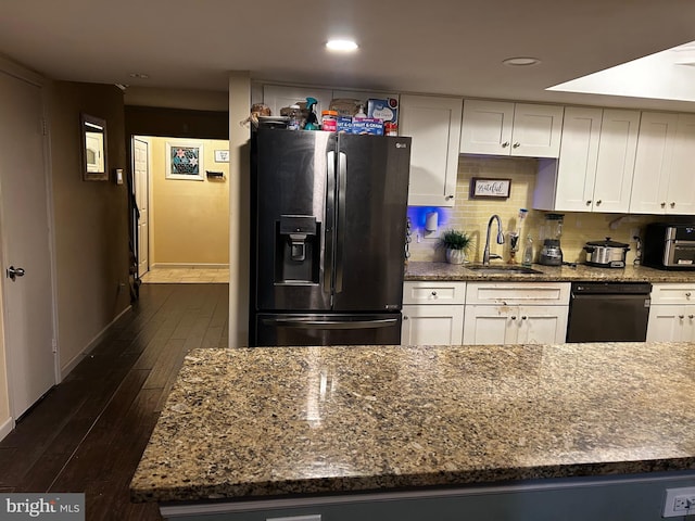 kitchen with backsplash, stainless steel fridge, white cabinetry, and sink