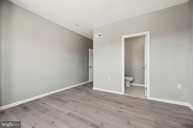 unfurnished bedroom featuring light wood-type flooring and connected bathroom