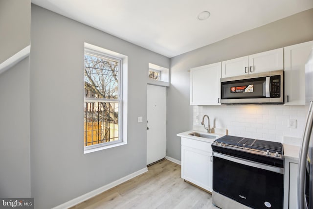 kitchen with sink, white cabinetry, stainless steel appliances, and a wealth of natural light