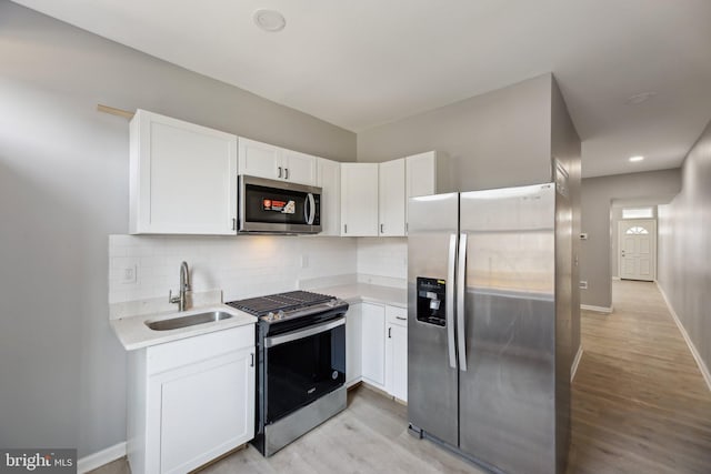 kitchen featuring white cabinetry, sink, stainless steel appliances, and light hardwood / wood-style floors