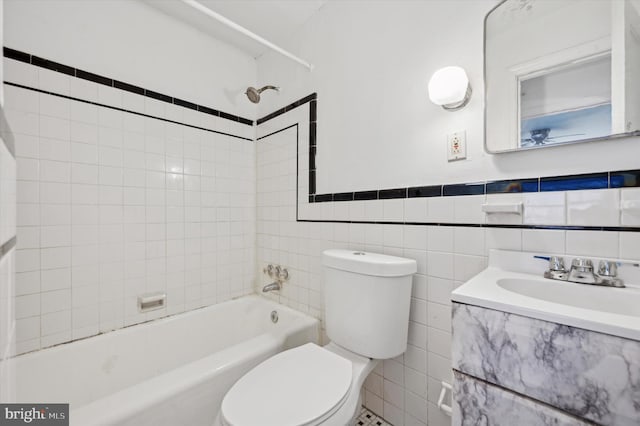 full bathroom featuring vanity, toilet, tile walls, and tiled shower / bath combo