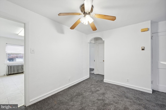 carpeted spare room featuring ceiling fan and radiator