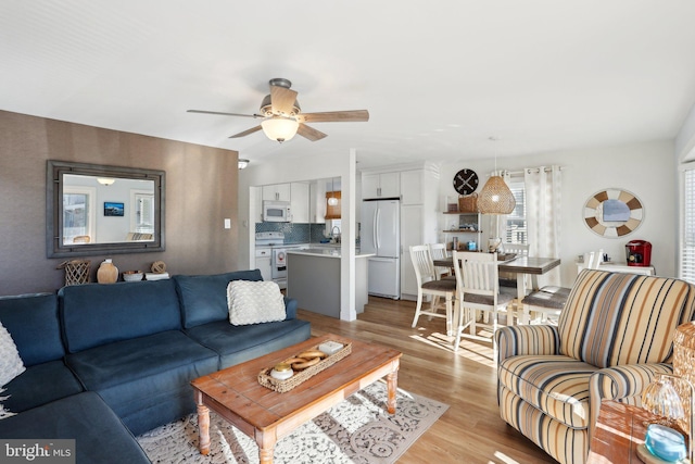 living room featuring light wood-type flooring, ceiling fan, and sink