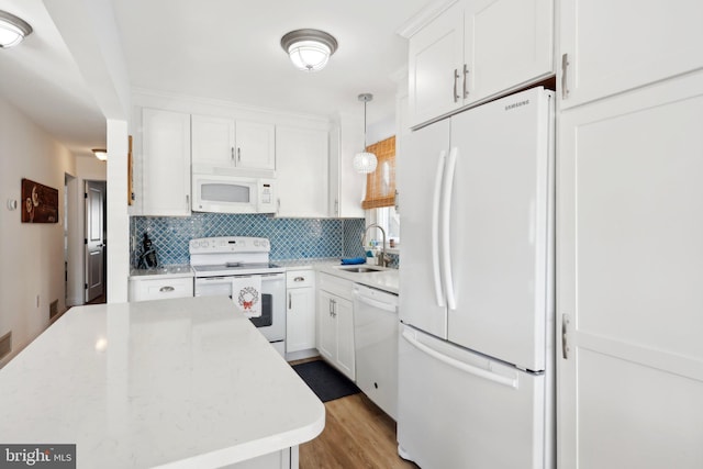 kitchen featuring white cabinetry, sink, pendant lighting, and white appliances