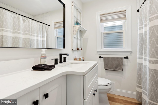 bathroom with hardwood / wood-style floors, vanity, a healthy amount of sunlight, and toilet