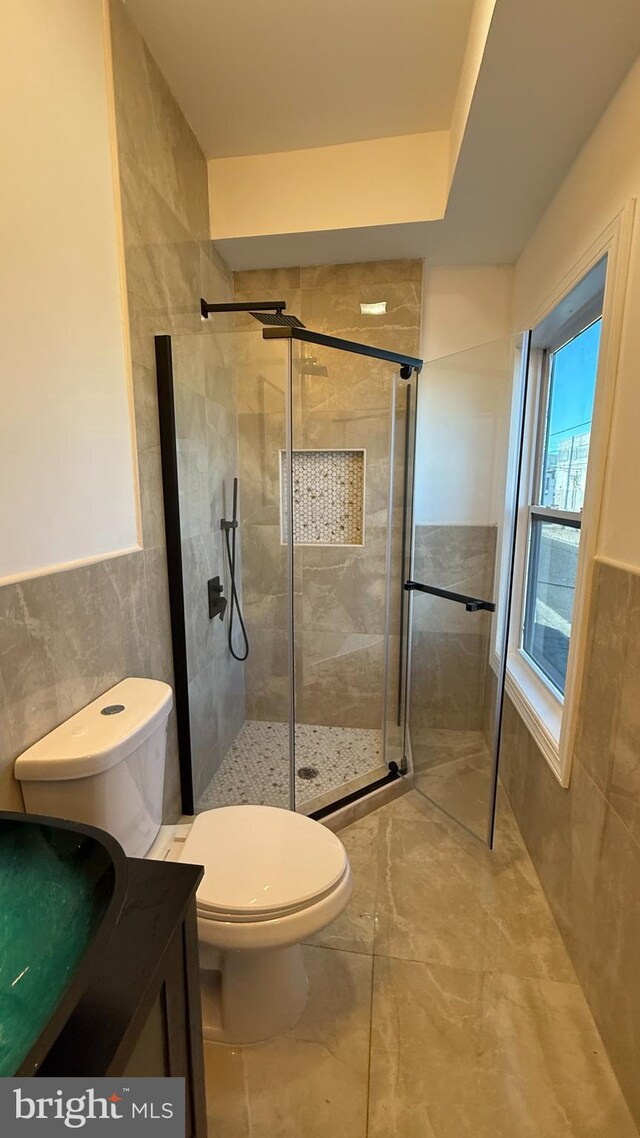 bathroom featuring vanity, toilet, walk in shower, and tile walls