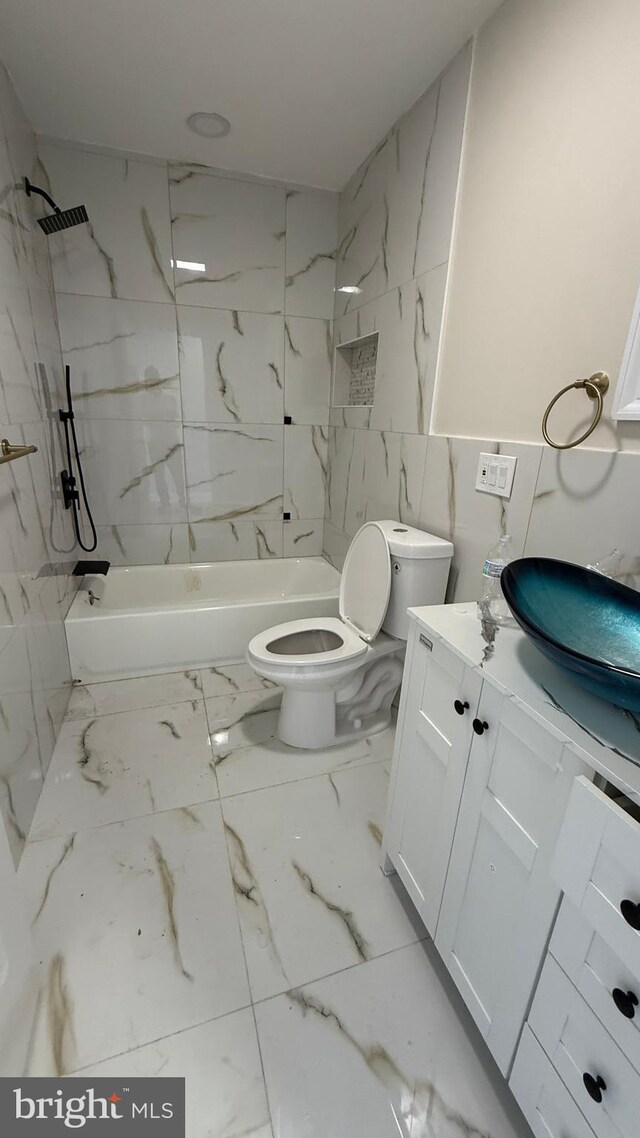 full bathroom featuring vanity, tiled shower / bath combo, tile walls, and toilet