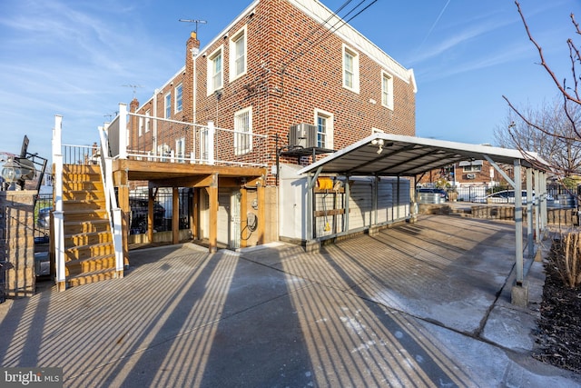 exterior space with central air condition unit, a wooden deck, and a carport