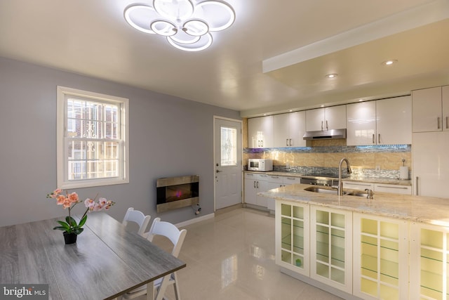 kitchen with white cabinetry, sink, light stone counters, decorative backsplash, and light tile patterned floors