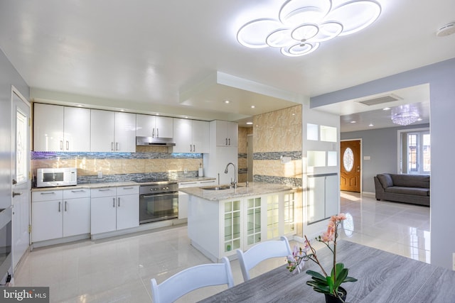 kitchen featuring white cabinetry, sink, backsplash, kitchen peninsula, and oven