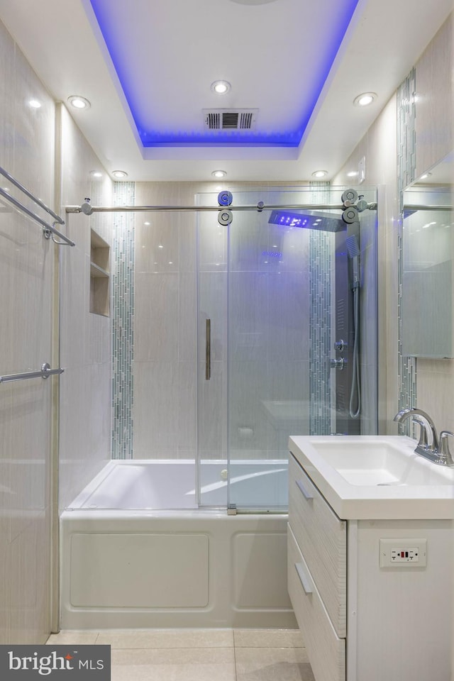 bathroom with vanity, a tray ceiling, tile patterned floors, and bath / shower combo with glass door