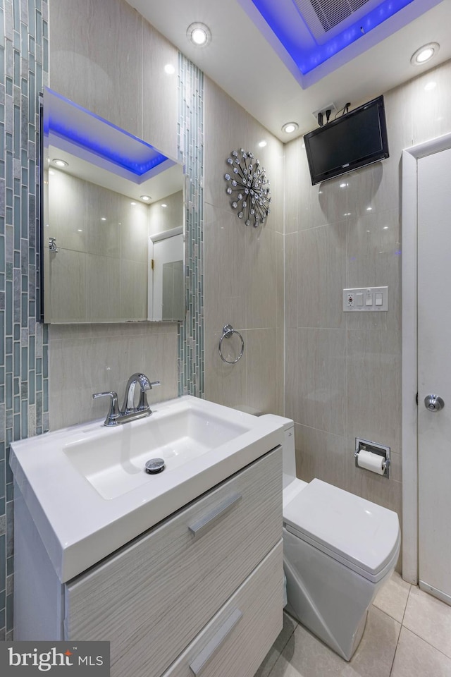 bathroom with tile patterned flooring, vanity, tile walls, and toilet