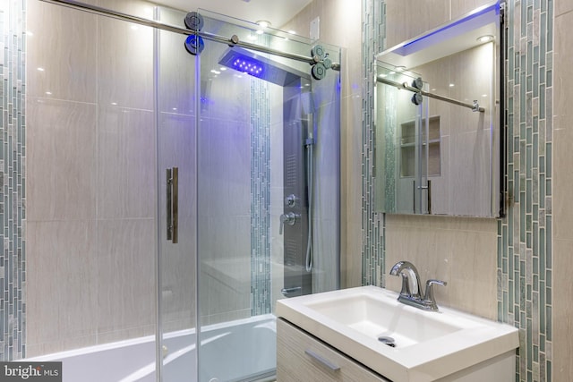 bathroom with vanity, combined bath / shower with glass door, and backsplash