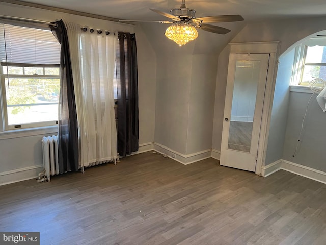 empty room featuring radiator heating unit, ceiling fan, and hardwood / wood-style floors