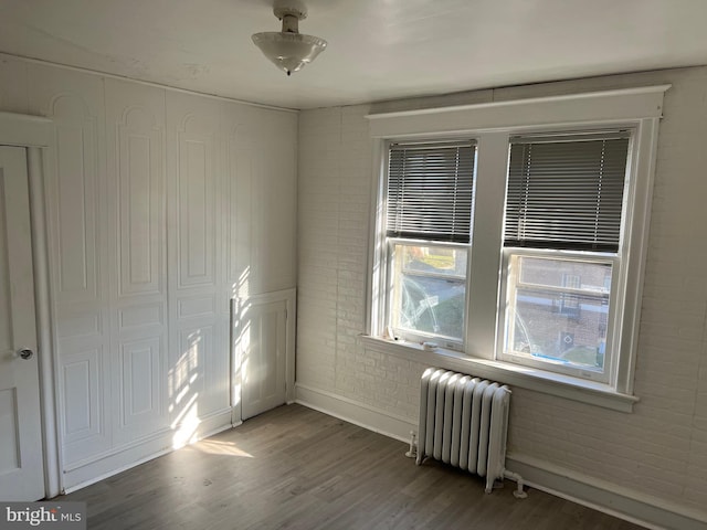 spare room with dark wood-type flooring and radiator