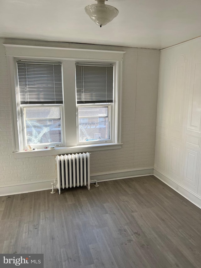 spare room featuring hardwood / wood-style floors and radiator heating unit